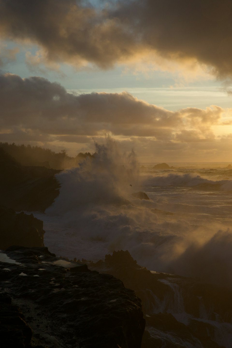 Ocean waves crash on rocky coastline at sunset.
